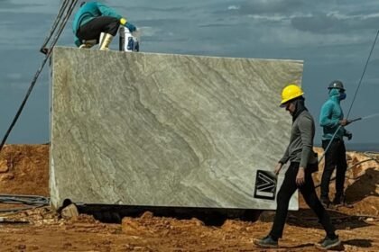 Trabalhadores utilizam equipamentos de proteção enquanto manuseiam um grande bloco de quartzito em área de extração no Ceará, rocha que lidera as exportações minerais do Estado em 2025.