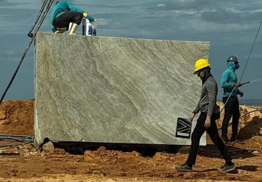 Trabalhadores utilizam equipamentos de proteção enquanto manuseiam um grande bloco de quartzito em área de extração no Ceará, rocha que lidera as exportações minerais do Estado em 2025.