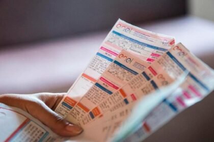 Mão segura várias contas de energia da Enel, ilustrando o novo desconto concedido a famílias inscritas no CadÚnico.
