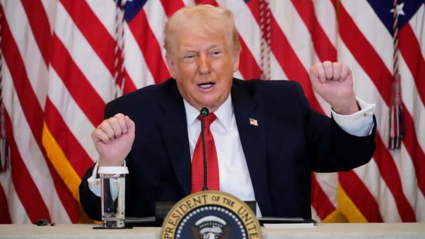 Donald Trump fala ao microfone em mesa oficial da Casa Branca, com bandeiras dos Estados Unidos ao fundo, gesticulando com as mãos durante discurso.