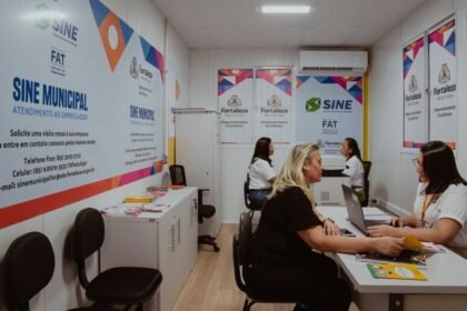 Interior de uma unidade do Sine Municipal de Fortaleza, com atendentes em mesas auxiliando pessoas em busca de emprego, em ambiente organizado com computadores e materiais informativos nas paredes.