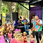 Crianças fantasiadas e famílias acompanham apresentação musical no Sivozinha Folia, em espaço aberto na Lagoa da Maraponga, em Fortaleza.