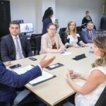 Autoridades e representantes de instituições sentados em mesa de reunião no Tribunal de Justiça do Ceará durante encontro para formalizar parceria sobre entrega voluntária para adoção.