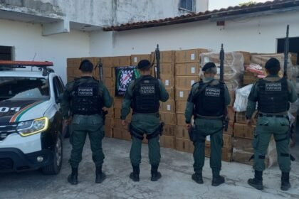 Policiais da Força Tática em frente a galpão com centenas de caixas de cigarros apreendidas em Pacajus, no Ceará.