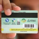 Mão segurando carteira estudantil com identificação do estudante, usada para acesso ao Passe Livre Estudantil e ao transporte público em Fortaleza.