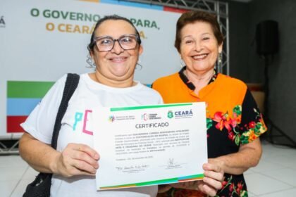 Mulher sorri segurando certificado de conclusão de curso profissionalizante ao lado de representante do Governo do Ceará, em cerimônia de qualificação profissional.
