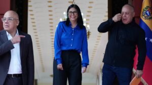 Delcy Rodríguez sorri entre Diosdado Cabello e Jorge Rodríguez no Palácio de Miraflores, em Caracas, antes de um pronunciamento oficial.