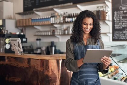 Mulher jovem sorrindo enquanto utiliza um tablet, representando o uso de tecnologia no empreendedorismo.