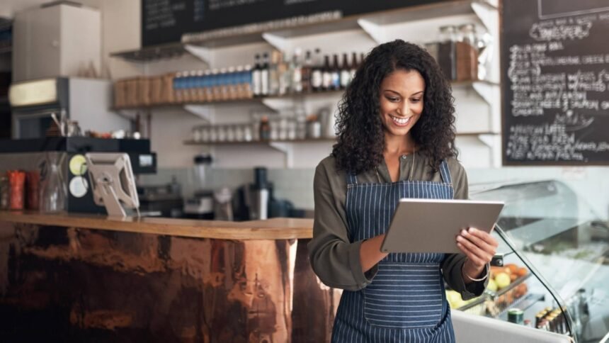 Mulher jovem sorrindo enquanto utiliza um tablet, representando o uso de tecnologia no empreendedorismo.