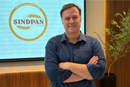 Presidente do Sindpan, Alex Martins, durante reunião na Casa da Indústria, em Fortaleza, ao lado do logotipo da entidade.