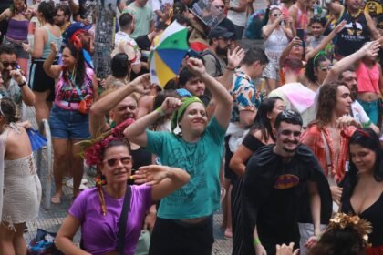 Foliões participam do Carnaval 2025 no polo do Benfica, em Fortaleza, mesmo sob chuva, dançando e celebrando a festa.