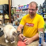 Décio Baccarini Neto, fundador da Raça & Ração, em pet shop durante atendimento, representando o crescimento dos pequenos negócios do mercado pet no Brasil.