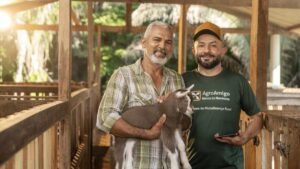 Agricultor familiar segura um cabrito ao lado de agente do Banco do Nordeste em ação do programa Agroamigo de microcrédito rural.