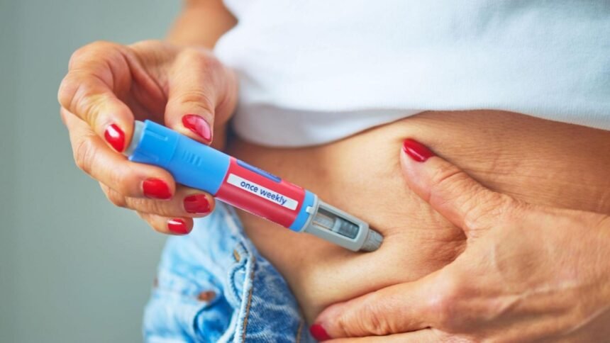 Pessoa aplicando caneta injetável para emagrecimento na região da barriga, medicamento da classe dos análogos de GLP-1. Canetas emagrecedoras.