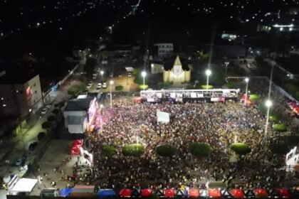 Vista aérea da Praça de São Francisco tomada por milhares de foliões durante o Carnaval 2026 de Cascavel, à noite, com palco iluminado e estrutura de evento.