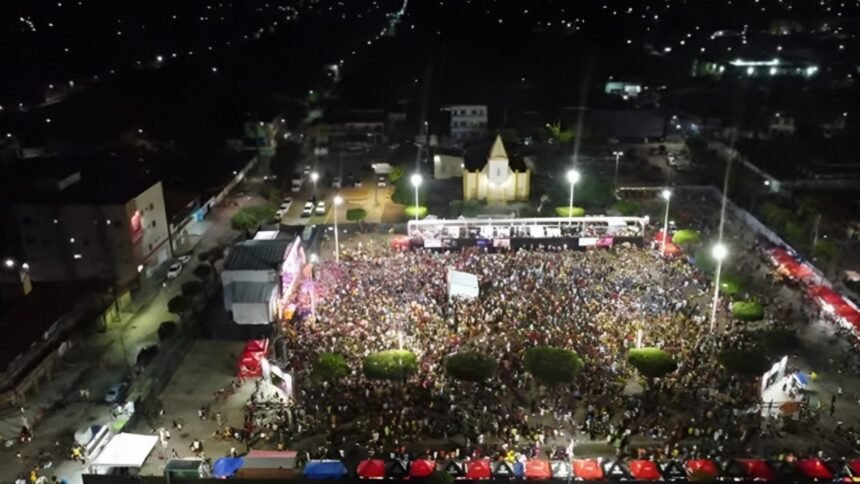 Vista aérea da Praça de São Francisco tomada por milhares de foliões durante o Carnaval 2026 de Cascavel, à noite, com palco iluminado e estrutura de evento.