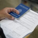 Pessoa segurando Carteira de Trabalho e Previdência Social sobre documentos, simbolizando geração de emprego no Ceará.