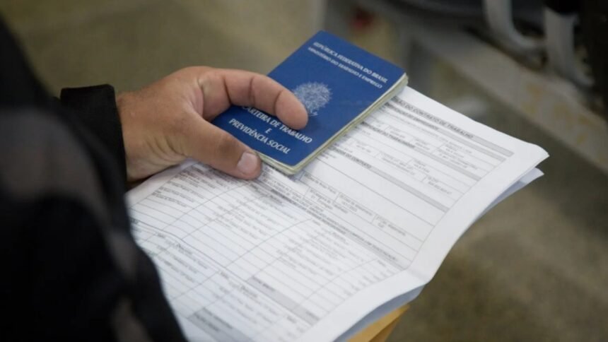 Pessoa segurando Carteira de Trabalho e Previdência Social sobre documentos, simbolizando geração de emprego no Ceará.