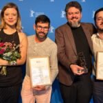 Cineastas cearenses premiados na Berlinale 2026 seguram troféus e certificados após conquista de três prêmios em Berlim.