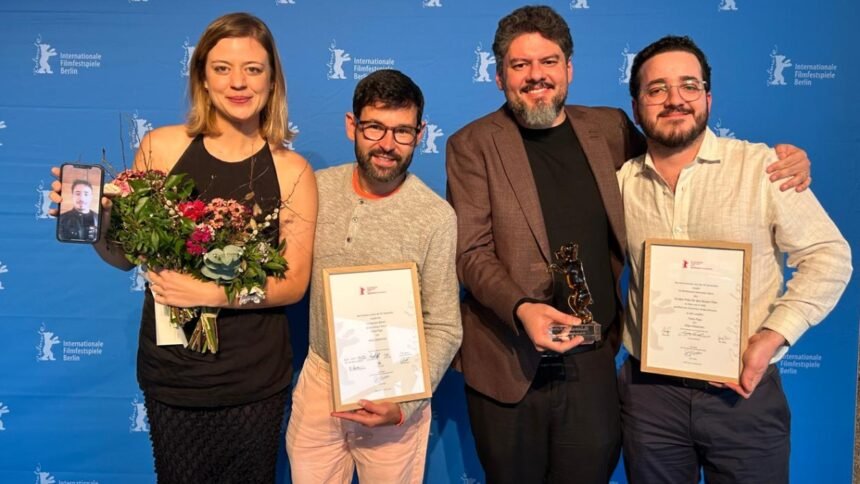 Cineastas cearenses premiados na Berlinale 2026 seguram troféus e certificados após conquista de três prêmios em Berlim.